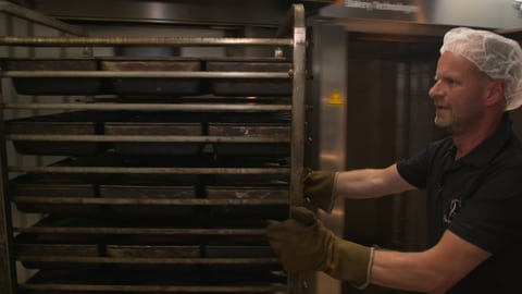 Bäcker Matthias Hofmann schiebt einen Backwagen mit ketogenem Brot in seiner Bäckerei.