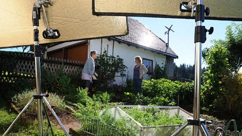 Bea und Johanna arbeiten im Garten, im Vordergrund Aufhellfolien für Kamera