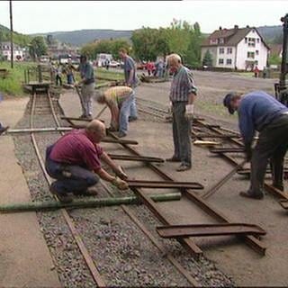 Mehrere  Männer beim Bau einer Bahnschiene.