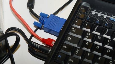 Zahlreiche Kabel stecken in einem Laptop.