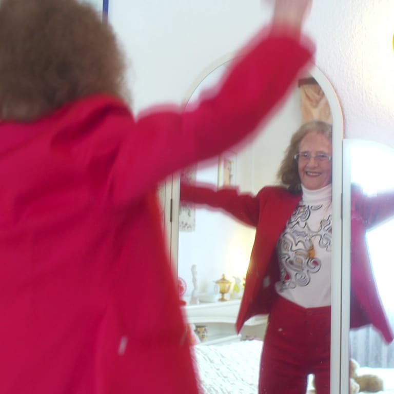 Ältere Frau tanzt vor Spiegel