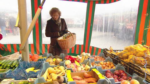 Frau an Marktstand , vor sich verschiedene, marktfrische Gemüsesorten