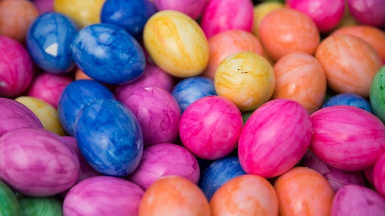 Bunt gefärbte, hartgekochte Eier liegen in einem Korb.