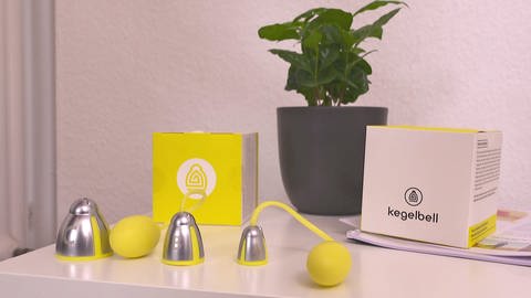 Gelbe Vaginalbälle mit Gewichten liegen auf dem Tisch. Über spezielle Technologien können Frauen ihrer Beckenbodenschwäche entgegenwirken.