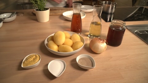 Verschiedene Zutaten für einen Kartoffelsalat liegen auf einem Tisch