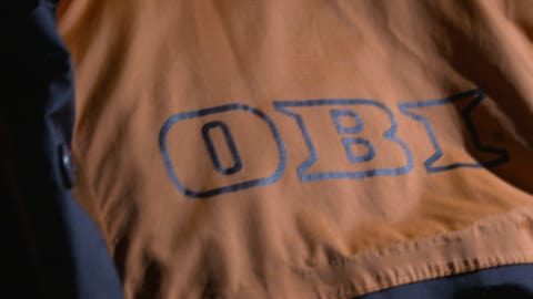 Ein orangenes Overall mit dem Logo der Baumarktkette Obi. Obi ist einer der beliebtesten Baumarktketten in Deutschland.