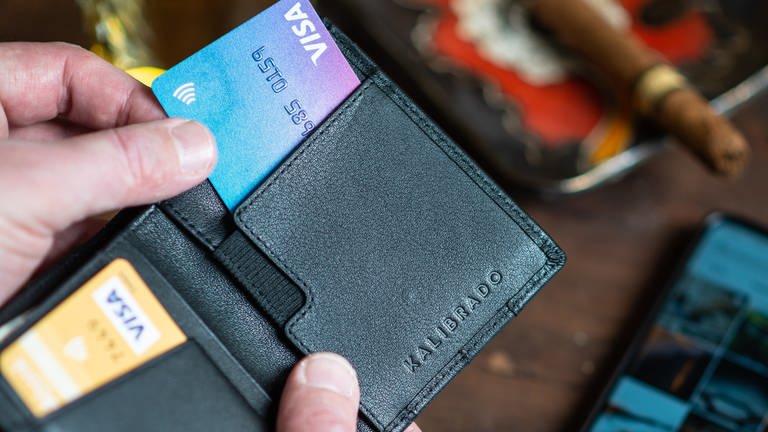 Mann zieht Kreditkarte aus einem Portemonnaie