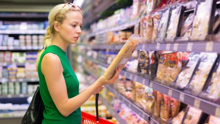 Eine Frau schaut auf die Lebensmittel im Supermarkt. Im Supermarkt fällt die Entscheidung oft schwer: Lieber das Markenprodukt oder doch die günstige Eigenmarke? (Foto: Colourbox)