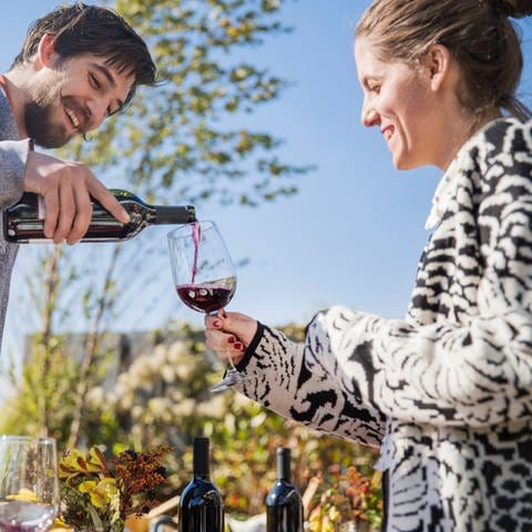 Zwei Menschen im Bild schenken sich Wein ein. Hat die Form des Glases Einfluss auf den Geschmack des Weins? Schmeckt Wein aus teuren Gläsern besser? 