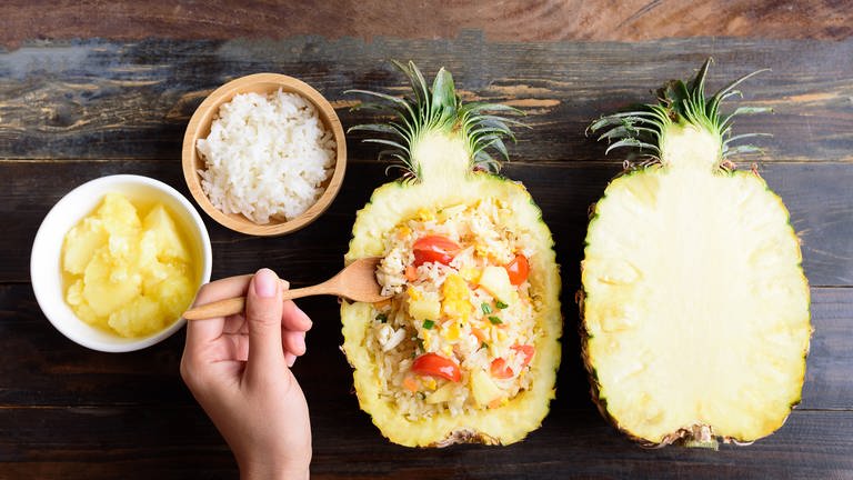 Reissalat, serviert in einer halben Ananas. Rezept für Reissalat mit Ananas, Chicorée, Paprika und Koriander (Foto: Adobe Stock)