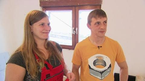 Ein Mann und eine Frau stehen auf einer Heimwerkerbaustelle nebeneinander.