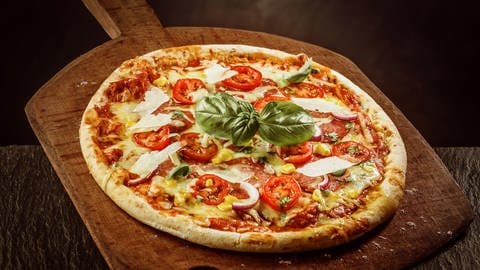 Pizza Margherita liegt auf einer großen Holzschaufel
