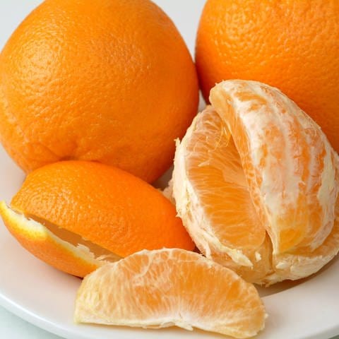 Orangen,Orangenschalen und geschälte Orangen liegen auf einem Teller