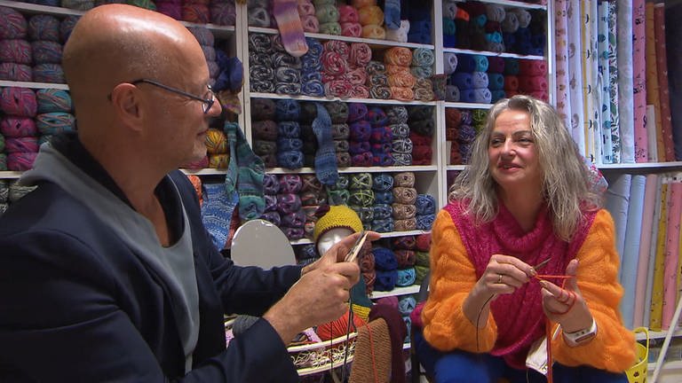 Eine Frau und Axel Gagstätter sitzen beim Stricken in einem Wolle-Laden in Hermaringen