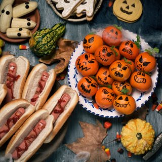 Auf Tellern liegen zu Gruselkürbissen dekorierte Mandarinen und Hotdogs, die wie abgeschlagene Finger aussehen (Foto: Colourbox, nito)