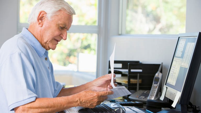 Alter Mann blickt auf einen Zettel, Schreibtisch, Rente, Frührente, Hinzuverdienst, Rentner (Foto: Colourbox)