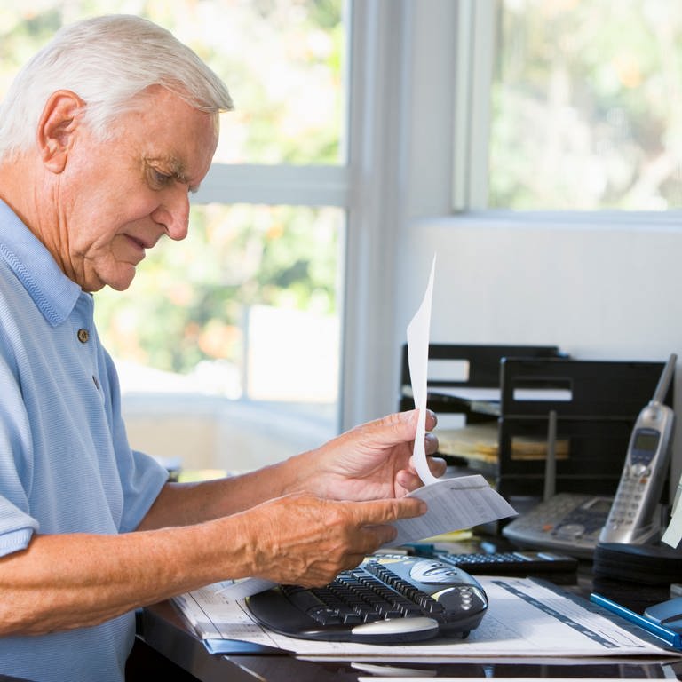 Alter Mann blickt auf einen Zettel, Schreibtisch, Rente, Frührente, Hinzuverdienst, Rentner (Foto: Colourbox)