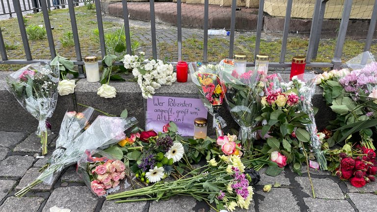 Menschen haben auf dem Mannheimer Marktplatz Blumen niedergelegt für die Opfer und Kerzen angezündet