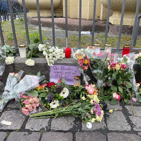 Menschen haben auf dem Mannheimer Marktplatz Blumen niedergelegt für die Opfer und Kerzen angezündet