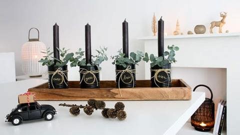 Etwas Grün, wie Moos oder Eucalyptus um die Kerzen herum stecken. Alle vier Dosen auf das Holztablett stellen und wer es gern üppiger mag, kann das Tablett mit zusätzlicher Dekoration bestücken. (Foto: Privat - Leoni Gehr)