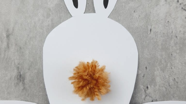 Kleben Sie den fertigen Bommel mit etwas Flüssigklebstoff auf die Rückseite des Hasen. (Foto: Lisa Vöhringer)