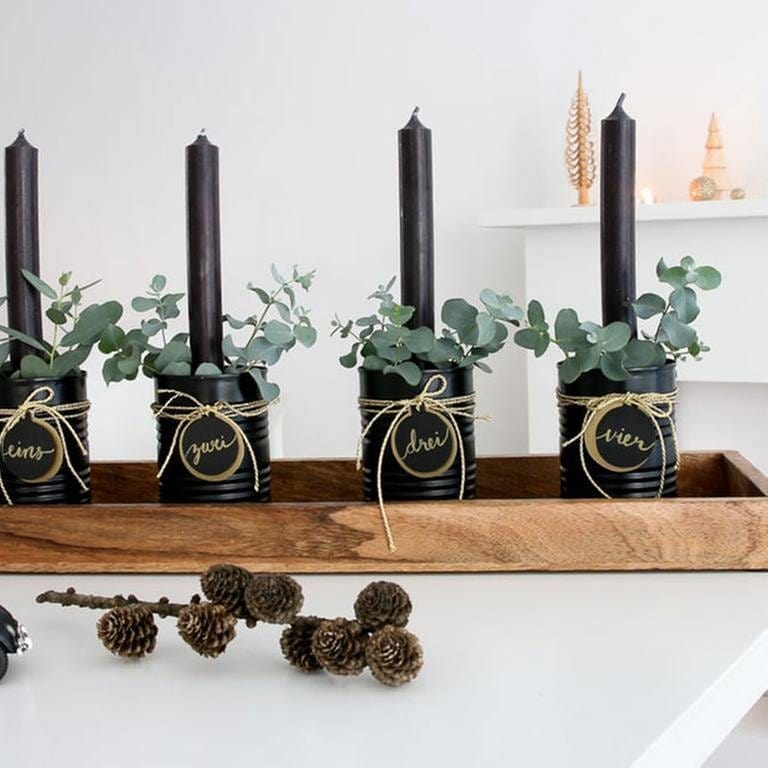 Etwas Grün, wie Moos oder Eucalyptus um die Kerzen herum stecken. Alle vier Dosen auf das Holztablett stellen und wer es gern üppiger mag, kann das Tablett mit zusätzlicher Dekoration bestücken. (Foto: Privat - Leoni Gehr)