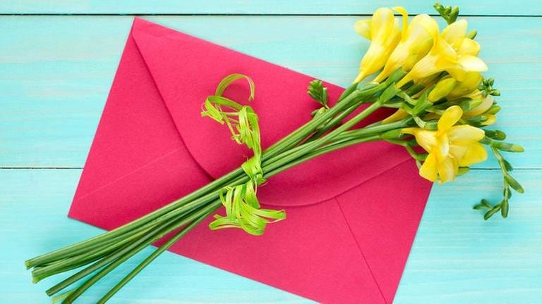 Ein Bund gelber Freesien auf einem pinkfarbenen Briefumschlag. (Foto: Colourbox, Foto: Colourbox.de -)