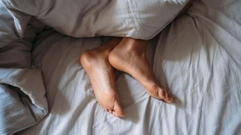 Füße unter Bettdecke (Foto: Colourbox)