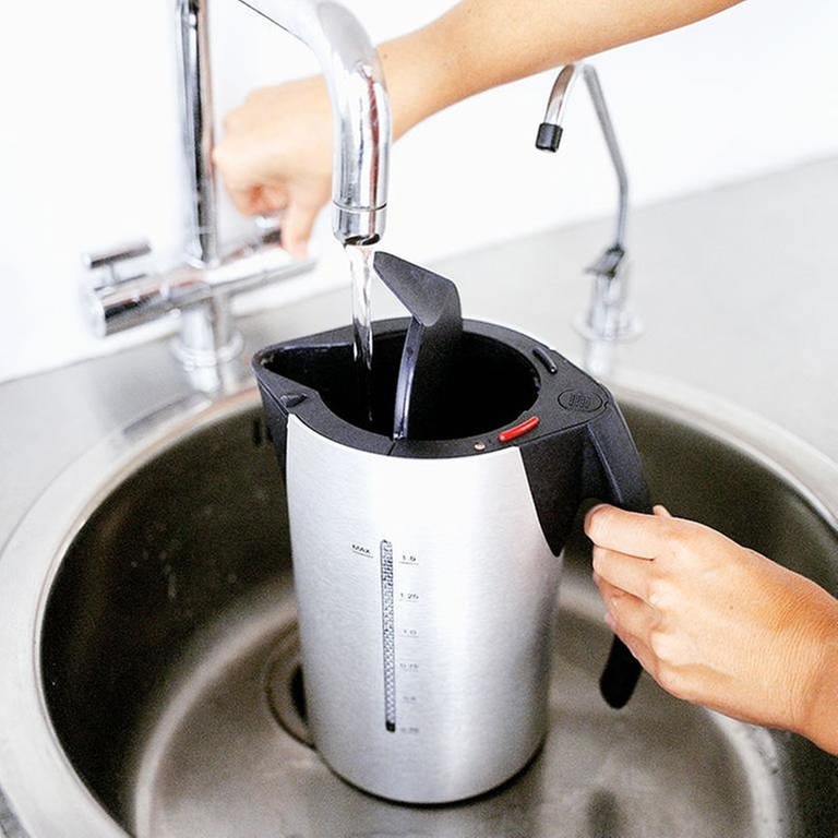 Frauenhände befüllen einen Wasserkocher unter dem Wasserhahn in der Küche. (Foto: Getty Images, Thinkstock -)