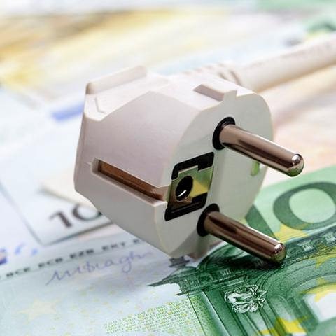 Verschiedene Euro Geldscheine liegen unter einem Steckdosenstecker.
