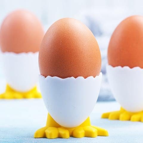 Drei gekochte Eier in Eierbechern.