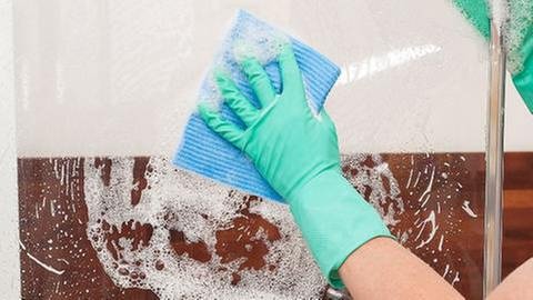 Eine Frau putzt die Scheibe einer Dusche (Foto: Getty Images, Thinkstock -)