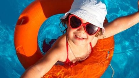 Lachendes Mädchen im Schwimmbad mit Rettungsring, Sonnenbrille und Hut. (Foto: Getty Images, Thinkstock -)