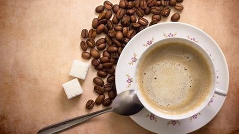 Eine Tasse Kaffee, daneben ein Löffel, Zucker und Kaffebohnen (Foto: Colourbox, Foto: Colourbox.de -)