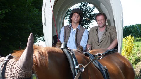 Matthias und Bernd fahren auf einem Planwagen, der von Pferden gezogen wird (Foto: SWR)
