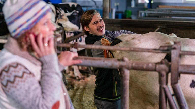 Sebastian untersucht eine Kuh, Bea steht telefonierend dabei (Foto: SWR, d:light/Christian Koch)