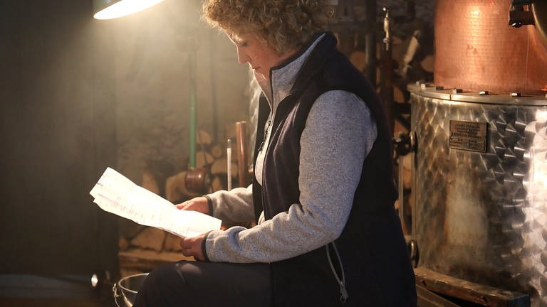 Bea sitzt am Brennofen und liest etwas (Foto: SWR, Johannes Krieg)