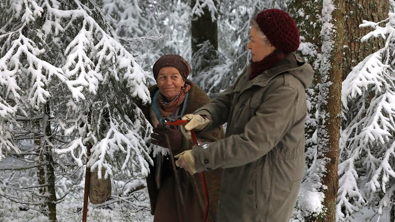 Johanna und Lioba im verschneiten Wald, Johanna hält eine Säge (Foto: SWR, Johannes Krieg)