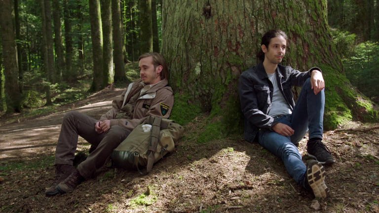 Sebastian und Albert sitzen an einen Baum gelehnt im Wald (Foto: SWR)