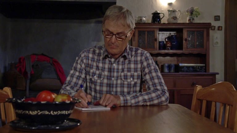 Karl sitzt am Küchentisch und schreibt einen Brief (Foto: SWR)