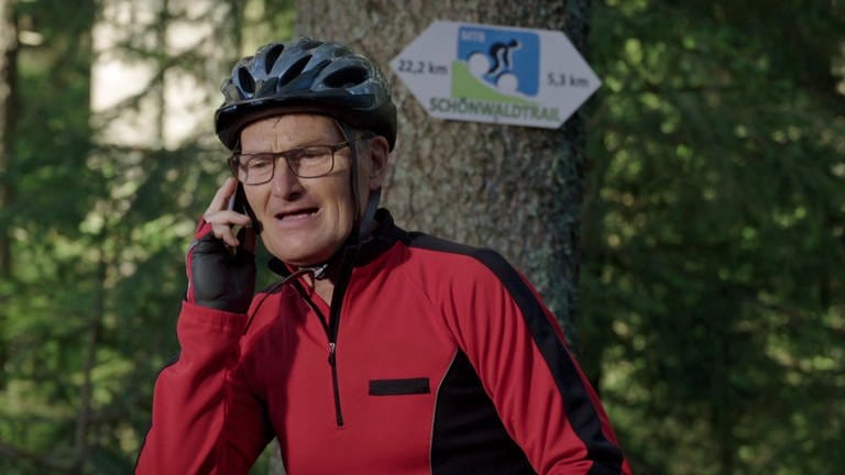 Karl steht in Fahrradmontur mit Helm im Wald und telefoniert (Foto: SWR)