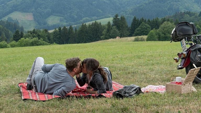 Andreas und Eva liegen auf ihrer Picknickdecke und küssen sich (Foto: SWR, SWR/Stephanie Schweigert -)