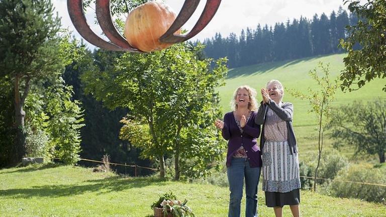 Johanna und Bea bestaunen einen in einer Greifzange eines Schleppers hängenden Kürbis (Foto: SWR, SWR/Stephanie Schweigert -)