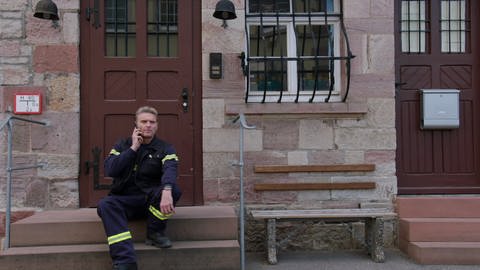 Uli Zimmermann sitzt auf dem Stufen vor dem Feuerwehrhaus (Foto: SWR)