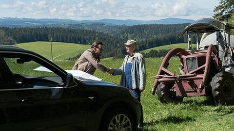 Constantin und Karl begrüßen sich auf freiem Feld, im Vordergrund Constantins Limousine, daneben Karls Traktor (Foto: SWR, SWR/Stephanie Schweigert -)