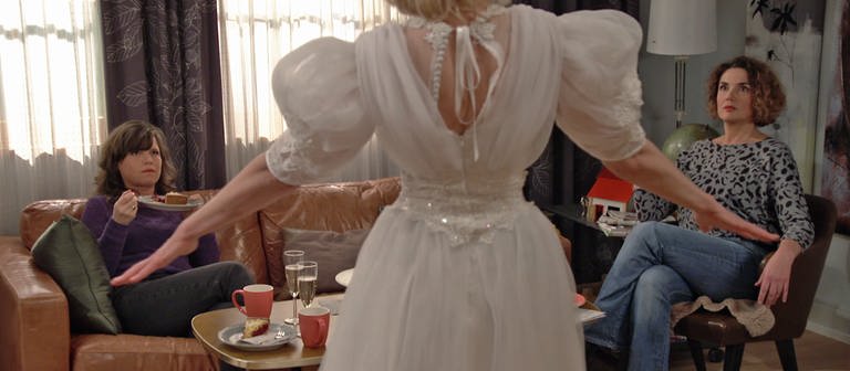 Kati präsentiert ein Brautkleid, Eva und Monique sitzen ihr entsetzt gegenüber (Foto: SWR)