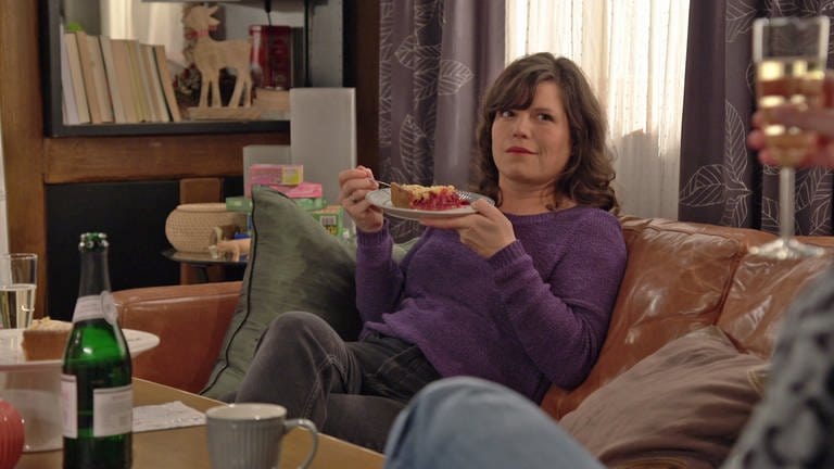 Eva sitzt auf dem Sofa und hält vor sich einen Teller mit Träubleskuchen (Foto: SWR)