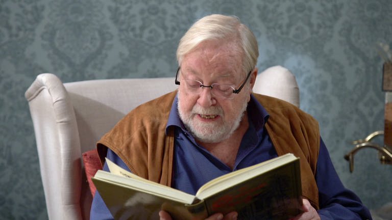 Hermann liest aus einem dicken Buch vor (Foto: SWR)