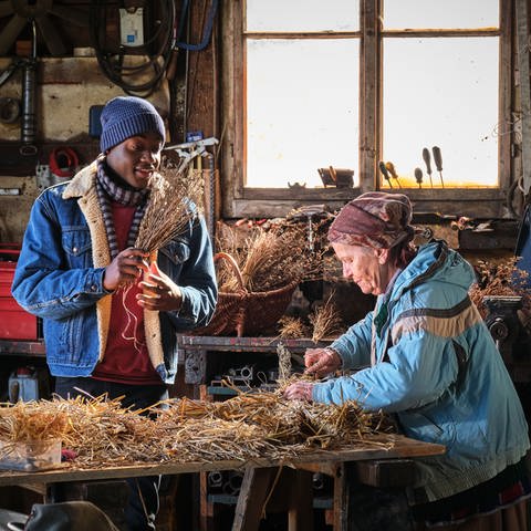 Lioba und Tayo bauen in der Traktorscheune gemeinsam an einer Strohpuppe (Foto: Benoit Linder)