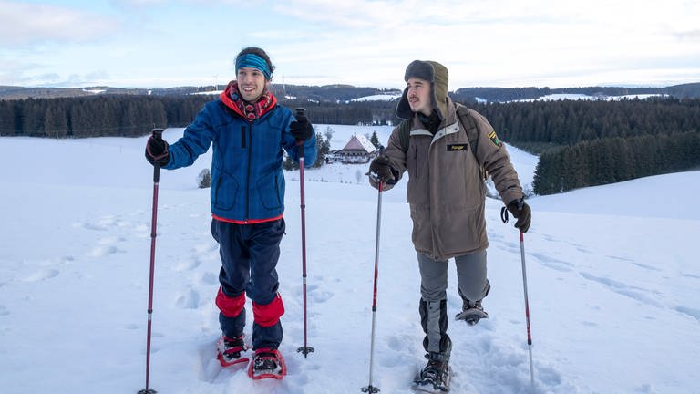 Albert und Sebastian wandern mit Schneeschuhen durchs Gelände, im Hintergrund liegt der Fallerhof (Foto: SWR, Alexander Kluge)